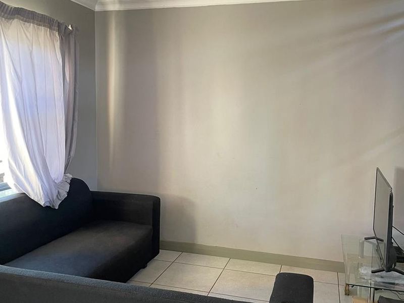 A living room area featuring tiled flooring and simple ceiling finishes, providing a functional space ready for cosmetic updates.