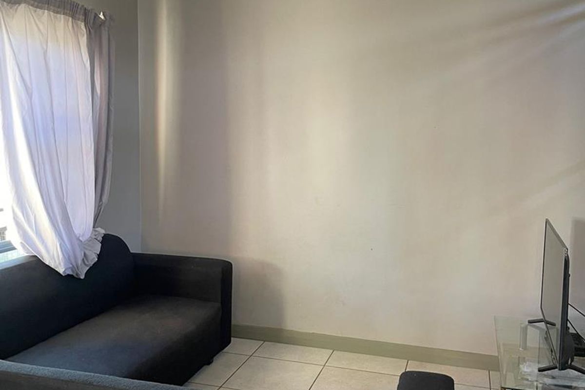 A living room area featuring tiled flooring and simple ceiling finishes, providing a functional space ready for cosmetic updates.