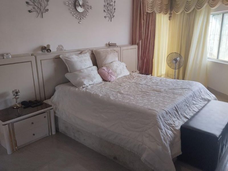 A bedroom featuring a built-in headboard and neutral finishes, offering a comfortable space with natural light from the window.