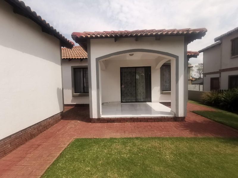 A covered patio area featuring tiled flooring, brick paving, and an arched entrance, providing a seamless transition to the garden space.