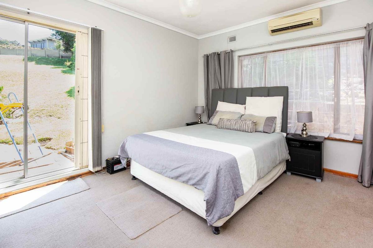 A bedroom featuring carpeted flooring, a split-system air conditioner, and a sliding glass door providing direct access to the rear garden area.
