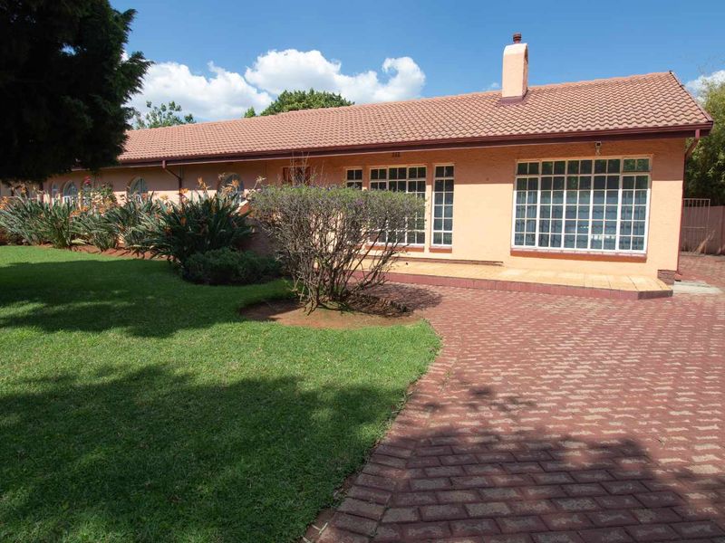 A well-maintained single-story home featuring a tiled roof, brick-paved driveway, and established garden with mature landscaping.