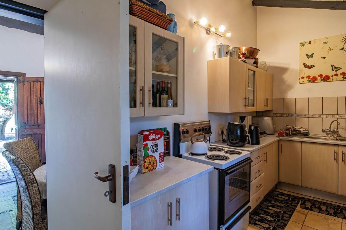 A functional kitchen featuring laminate cabinetry, an electric stove, and a tiled backsplash, with direct access to an outdoor patio area.