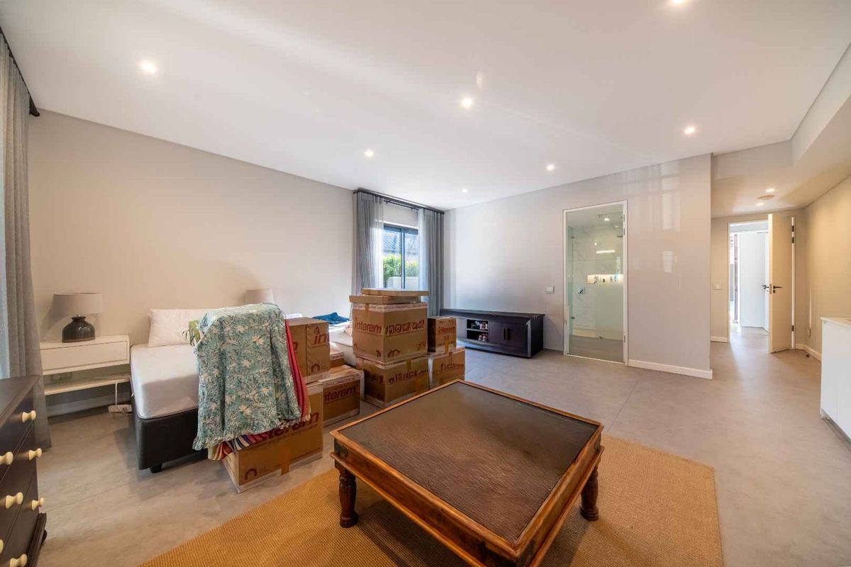 Spacious bedroom featuring modern tiled flooring, recessed downlighting, and an en-suite bathroom with a glass door entry.