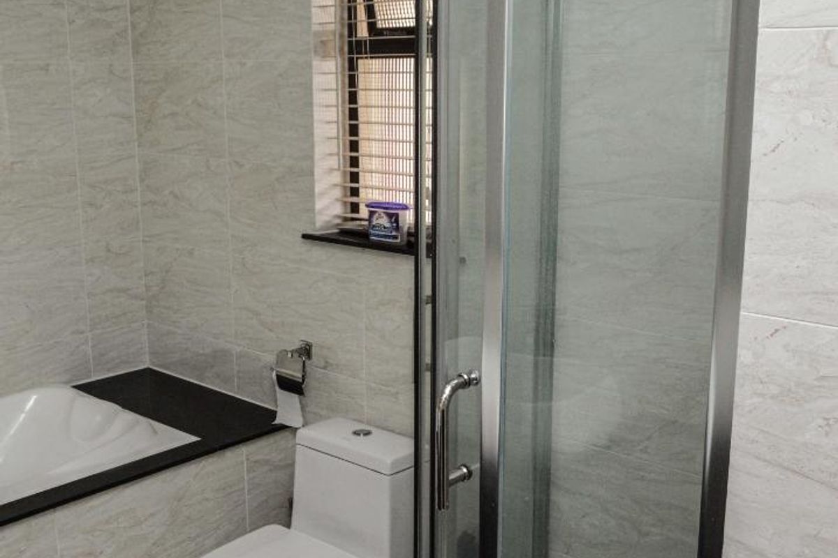 A modern bathroom featuring a glass-enclosed shower, a built-in bathtub, and a toilet, finished with neutral marble-look wall tiles and floor tiling.