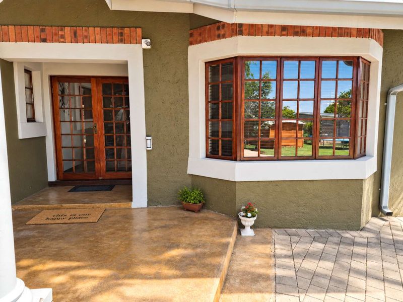 Front entrance featuring a covered concrete porch, double wooden doors, and a prominent bay window with brick detailing.