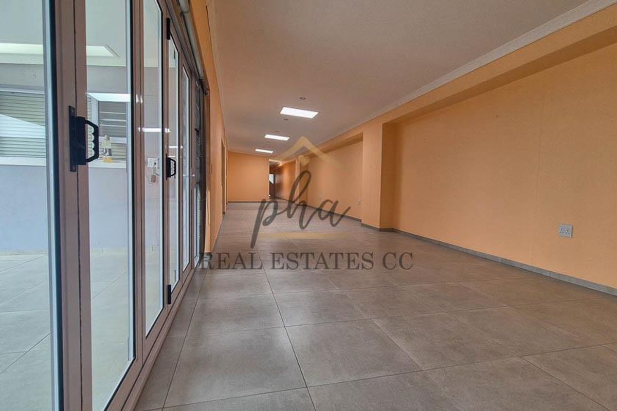 A spacious, empty living area featuring large aluminium stacker doors that open to the exterior, tiled flooring, and modern recessed downlighting.
