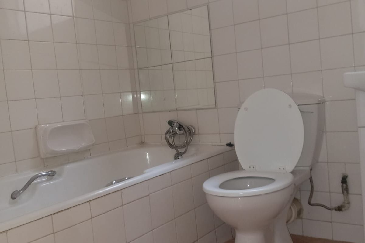 A functional bathroom featuring a bathtub, toilet, and tiled finishes. The space is ready for modernization and cosmetic updates.