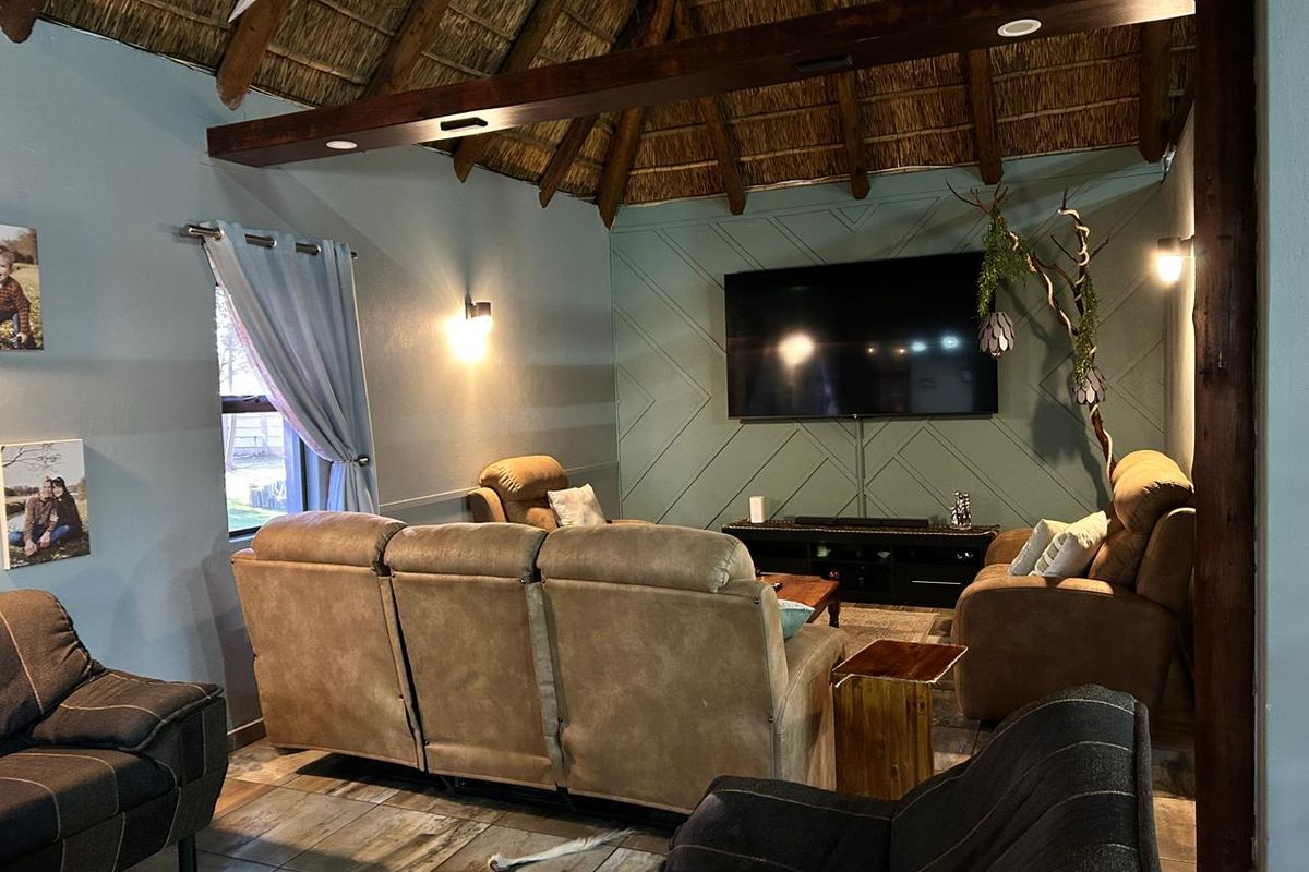 Cozy living room featuring a high vaulted thatched ceiling with exposed timber beams and a decorative paneled feature wall.