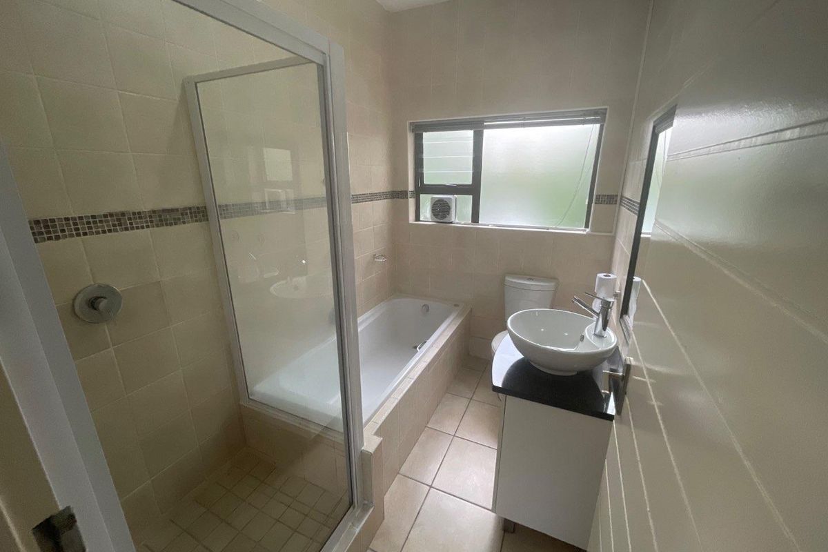 A functional bathroom featuring a separate shower enclosure, built-in bathtub, vanity with vessel sink, and neutral tiled finishes.