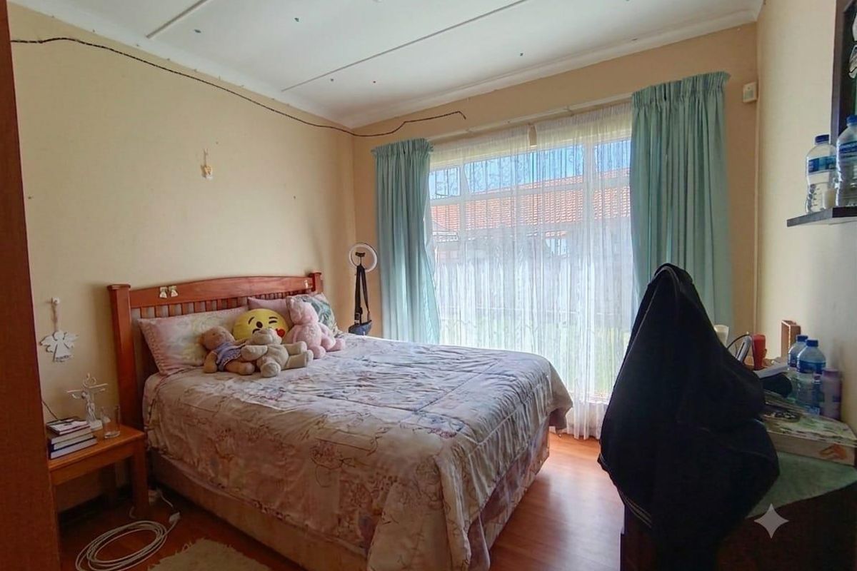 A standard bedroom featuring laminate flooring, large window with curtain tracks, and ceiling light fixture.