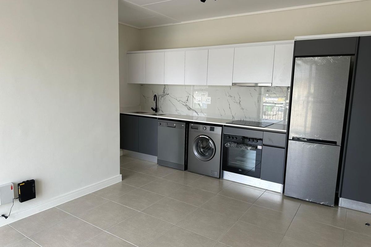 Modern open-plan kitchen featuring sleek two-tone cabinetry, marble-look splashback, integrated appliances, and neutral floor tiling in a contemporary apartment setting.