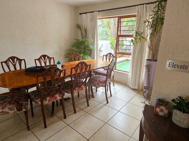 A dining room featuring tiled flooring and a window with views of the outdoor pool area.