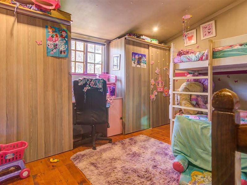 A bedroom featuring timber flooring and built-in cupboards, providing functional storage space.