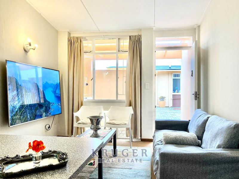 A bright living room featuring a large window and direct access to an outdoor patio area, providing natural light and easy indoor-outdoor flow.