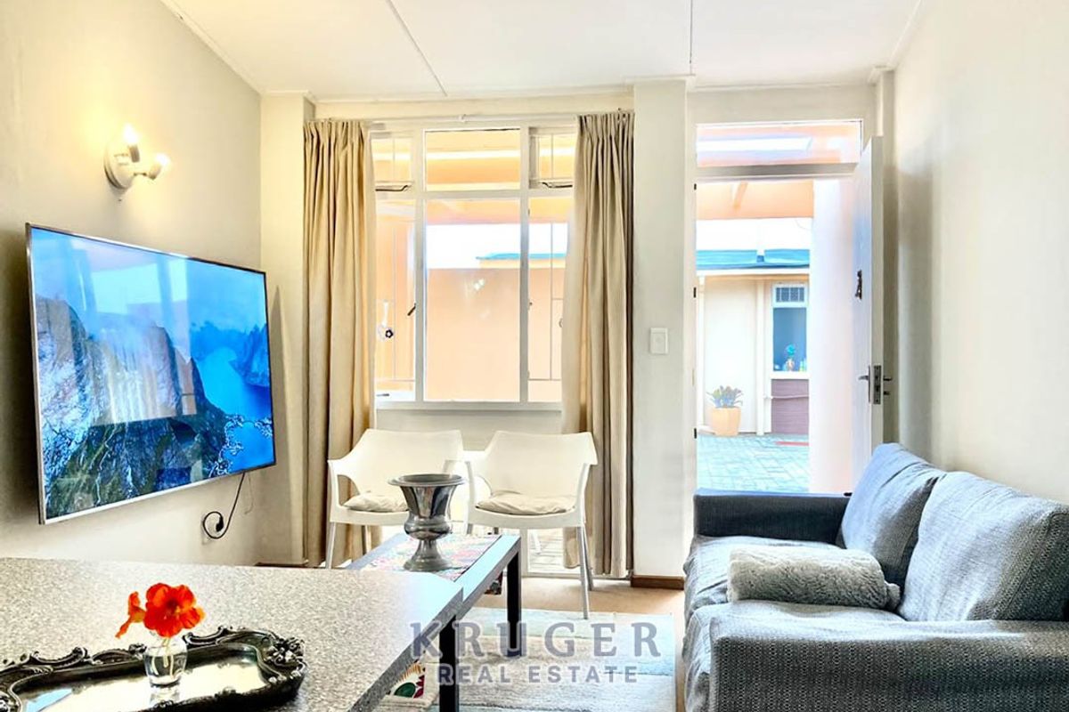 A bright living room featuring a large window and direct access to an outdoor patio area, providing natural light and easy indoor-outdoor flow.