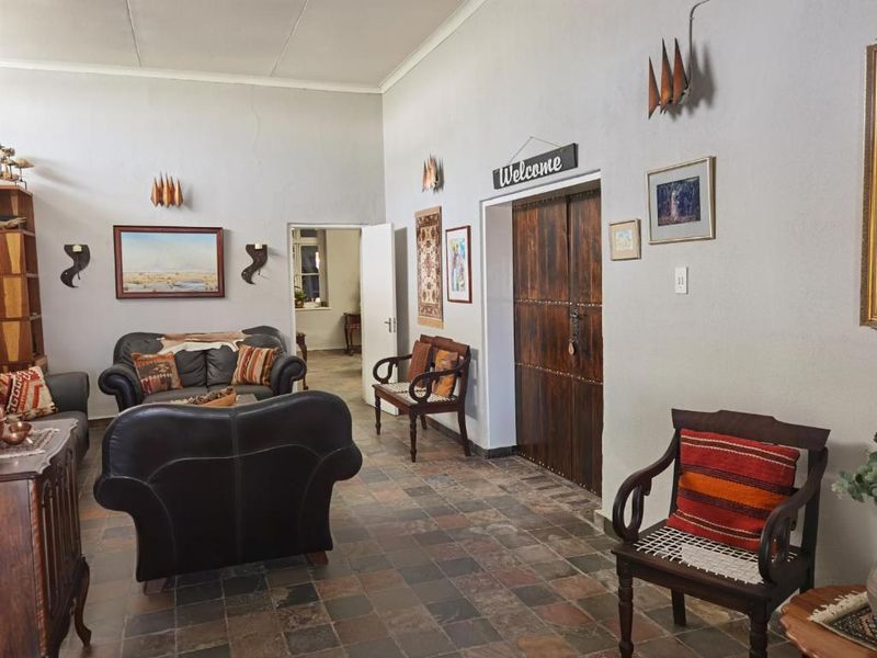 Spacious living area featuring rustic slate tile flooring and traditional double wooden doors, offering a warm and inviting atmosphere.