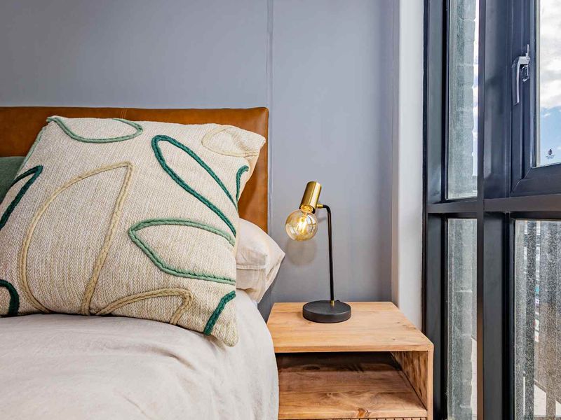 A well-lit bedroom corner featuring a large window with a modern black frame and neutral wall finishes.