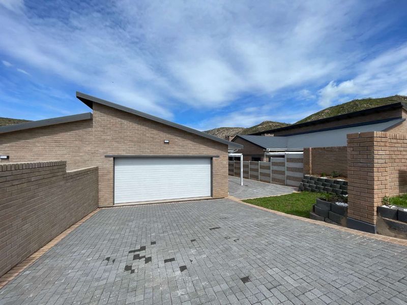 Modern brick exterior featuring a paved driveway, a clean sectional garage door, and well-maintained boundary walls with landscaped retaining elements.