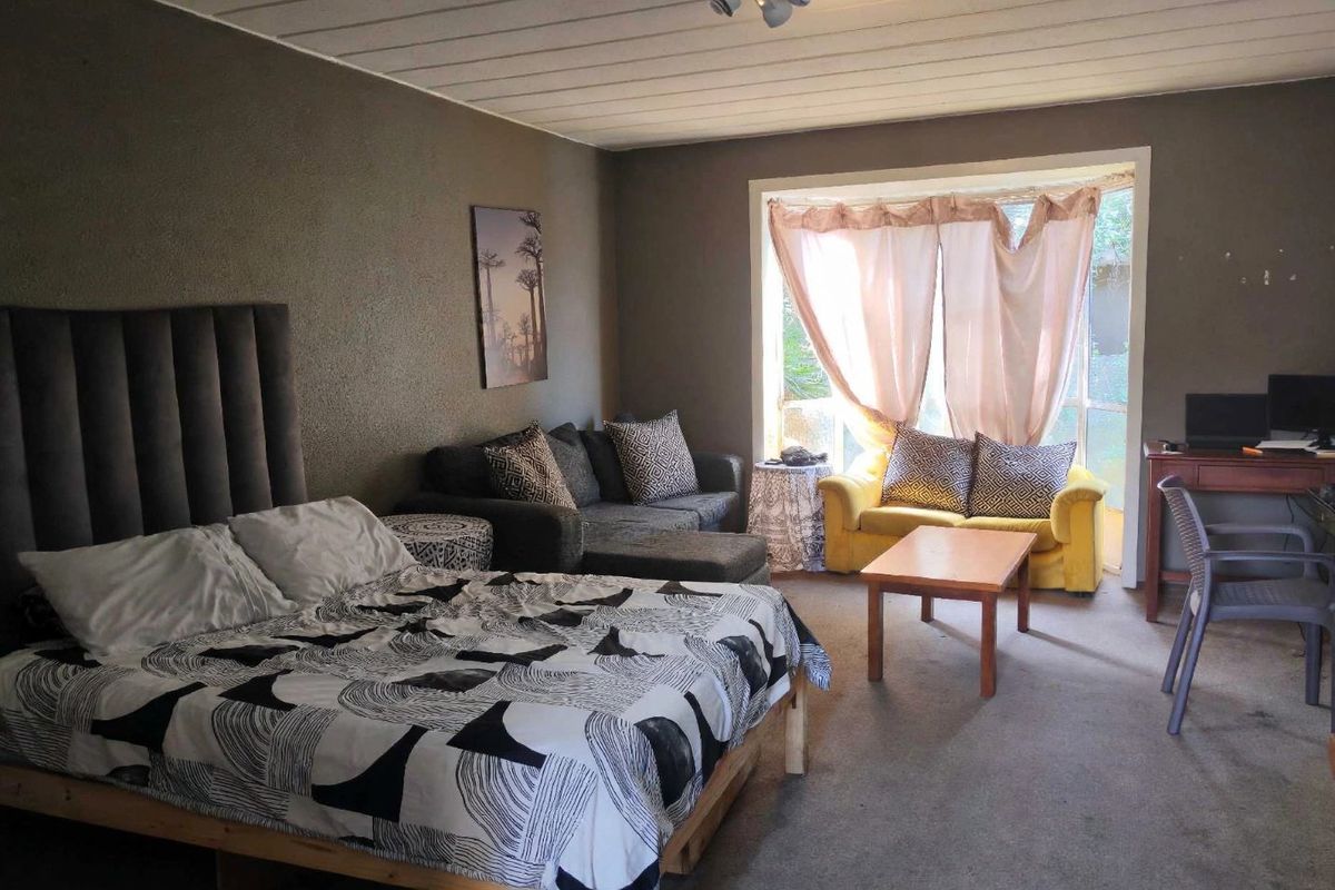 Spacious bedroom featuring a large window for natural light and a distinctive tongue and groove ceiling, offering a versatile layout for living and sleeping.