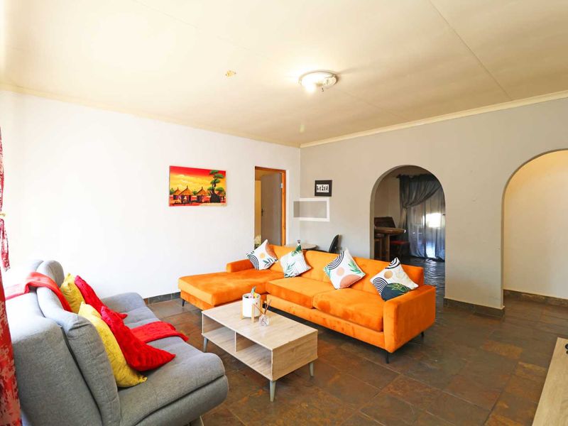 A living room featuring tiled flooring and distinctive arched doorways leading to adjacent spaces, providing a functional layout with potential for cosmetic updates.