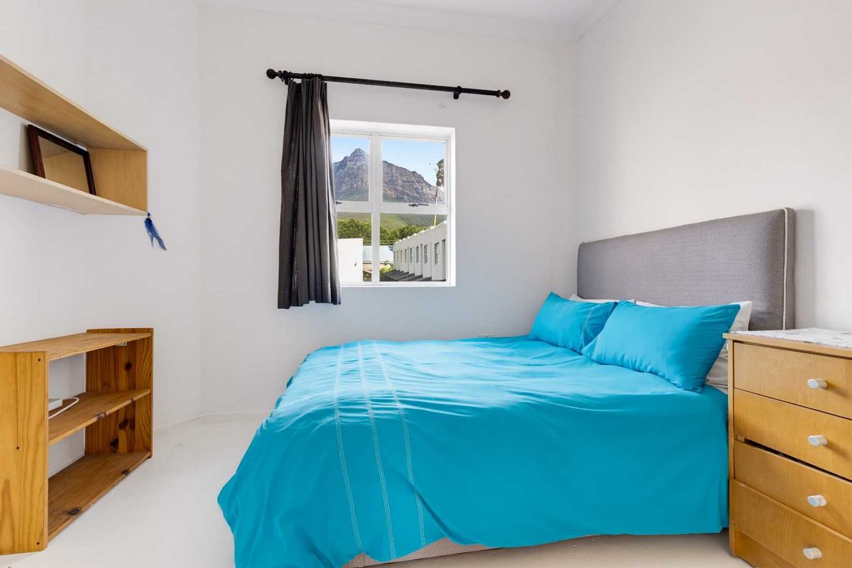 A bright bedroom featuring a window with mountain views, providing a simple and functional living space.