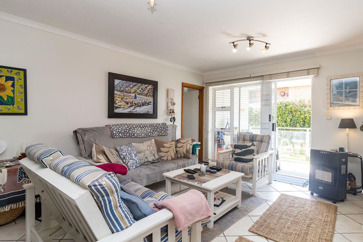 A bright living room featuring tiled flooring and a sliding glass door providing access to an outdoor patio area.