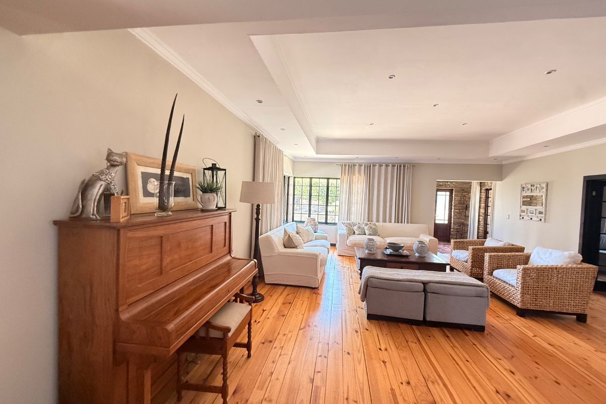Spacious living room featuring polished timber flooring, a recessed ceiling with downlights, and large windows allowing for ample natural light.
