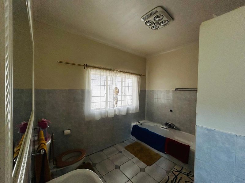 A functional bathroom featuring a bathtub, toilet, and basin with tiled walls and flooring, offering potential for a modern renovation.