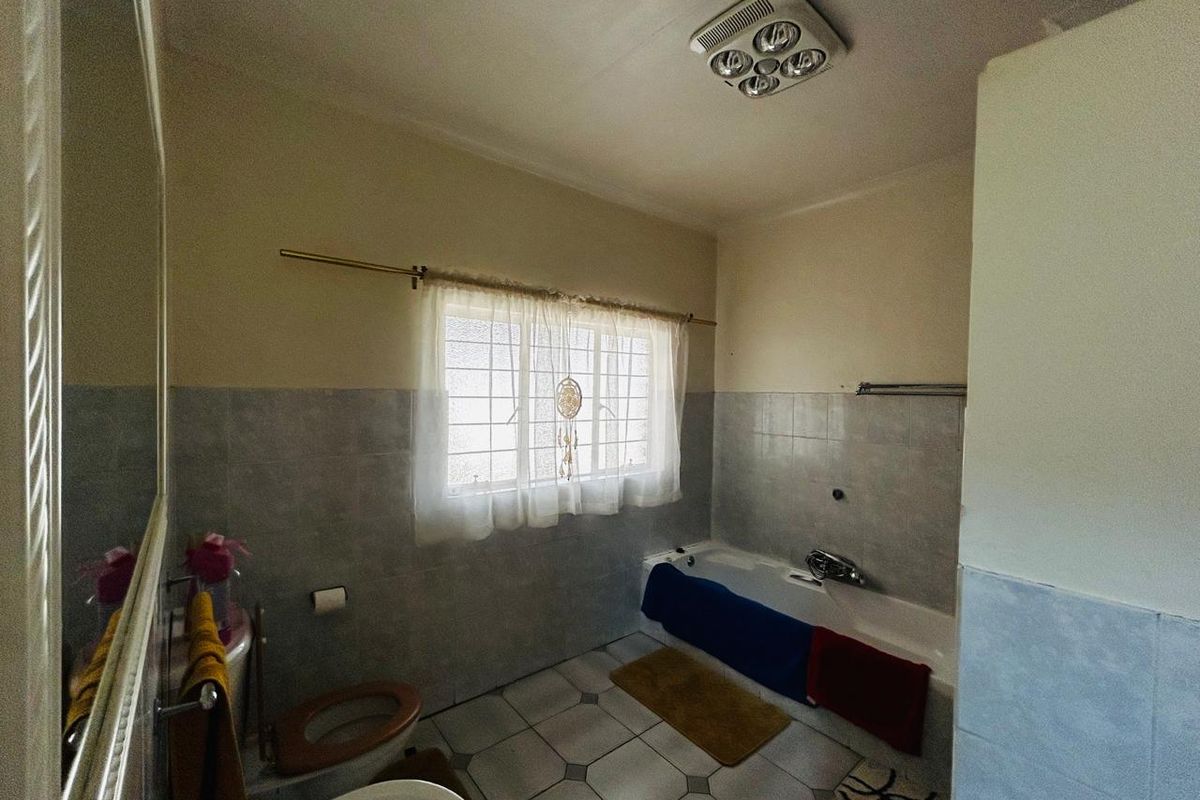 A functional bathroom featuring a bathtub, toilet, and basin with tiled walls and flooring, offering potential for a modern renovation.