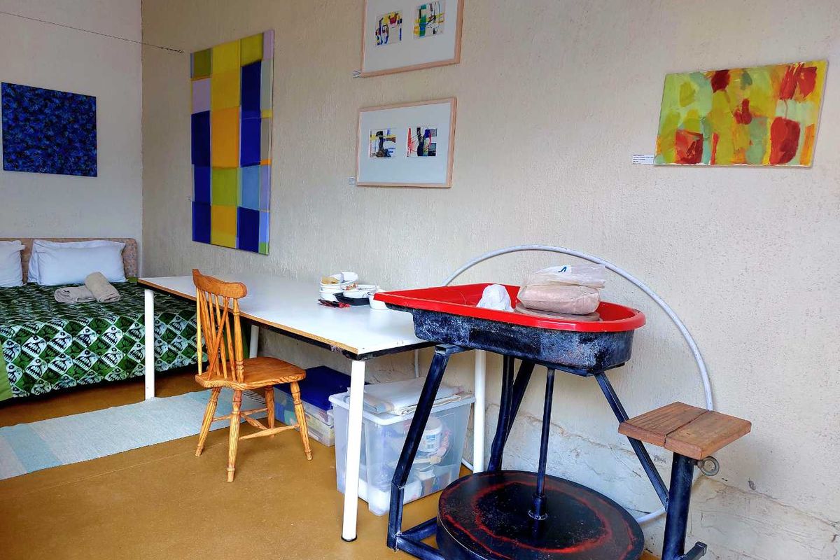 A multi-purpose room currently utilized as a studio and sleeping area, featuring textured walls and durable flooring.