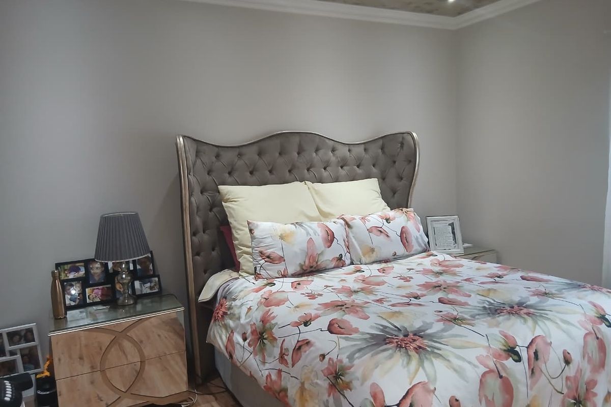 A well-maintained bedroom featuring recessed downlighting, coved ceiling details, and laminate flooring.