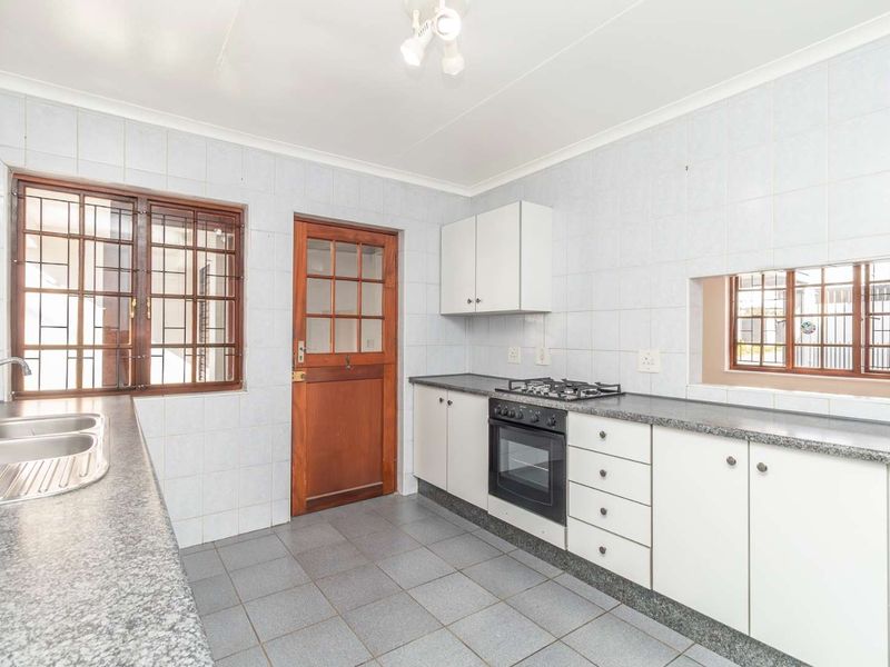 A functional kitchen featuring built-in cabinetry, laminate countertops, a gas hob, built-in oven, and tiled finishes throughout.
