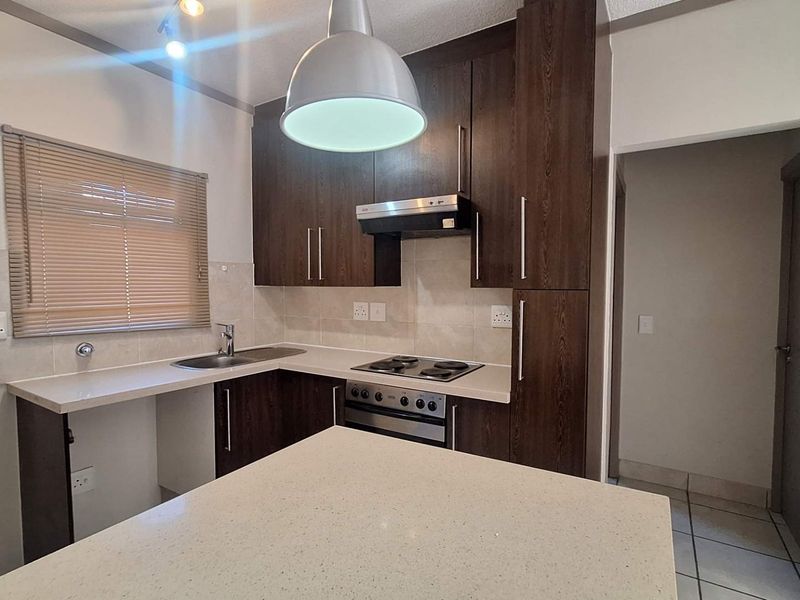 A functional kitchen featuring dark wood cabinetry, stone countertops, a built-in oven with hob, and a tiled backsplash.