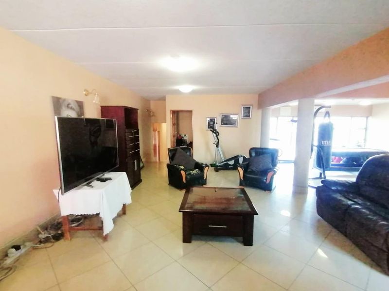 Spacious living area featuring tiled flooring and structural support columns, offering a versatile open-plan layout with potential for modern updates.