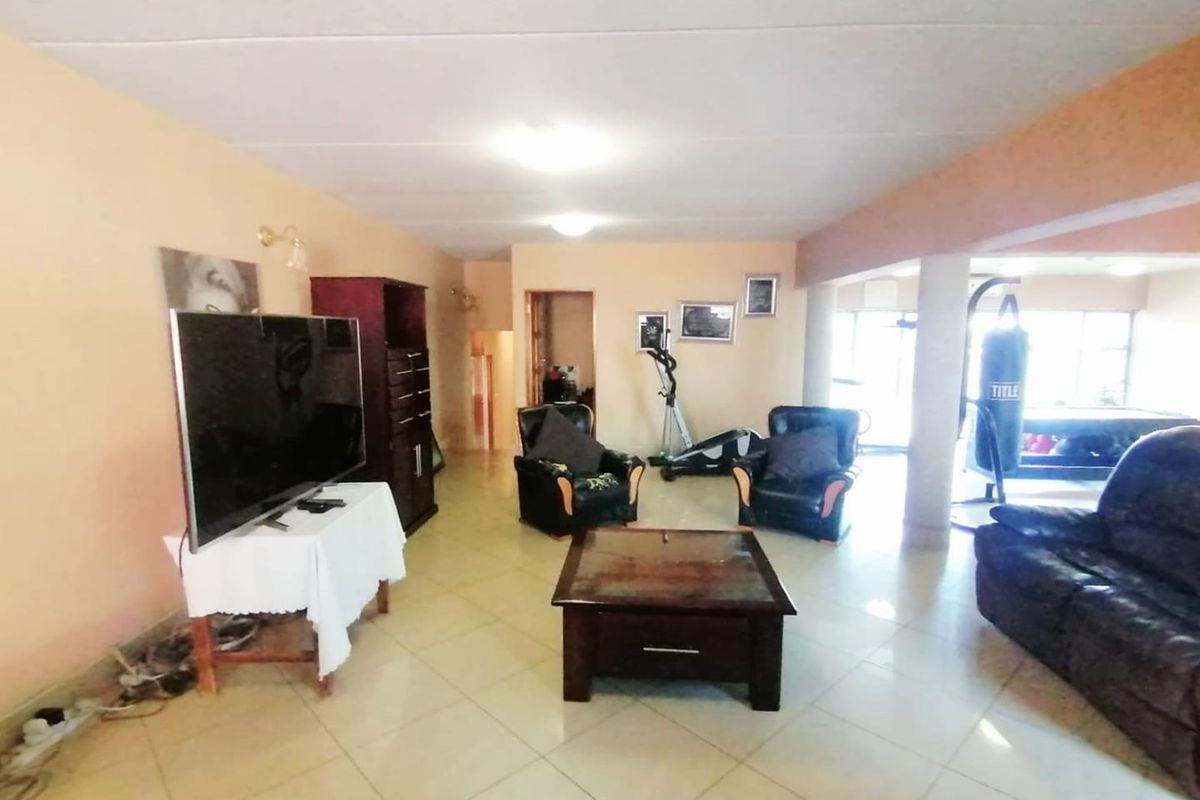 Spacious living area featuring tiled flooring and structural support columns, offering a versatile open-plan layout with potential for modern updates.
