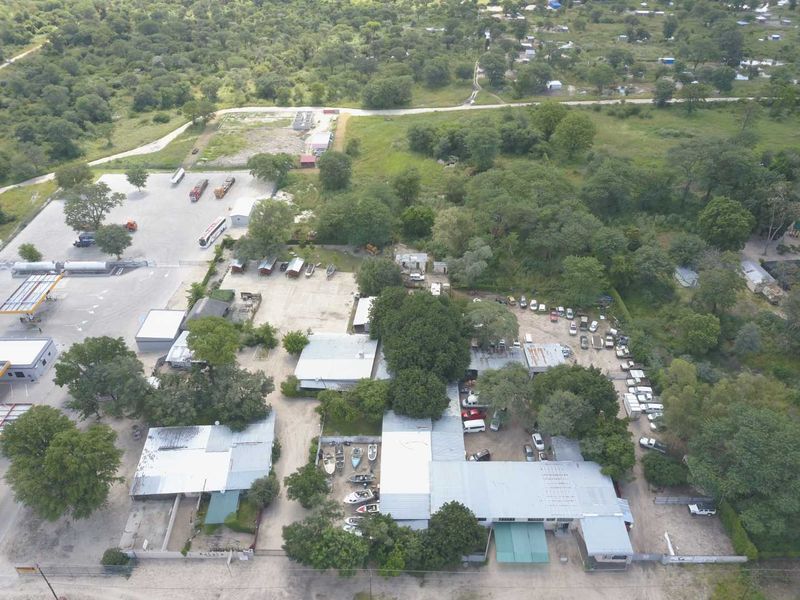 Aerial view of a mixed-use property featuring multiple structures, extensive parking areas, and surrounding natural landscape.