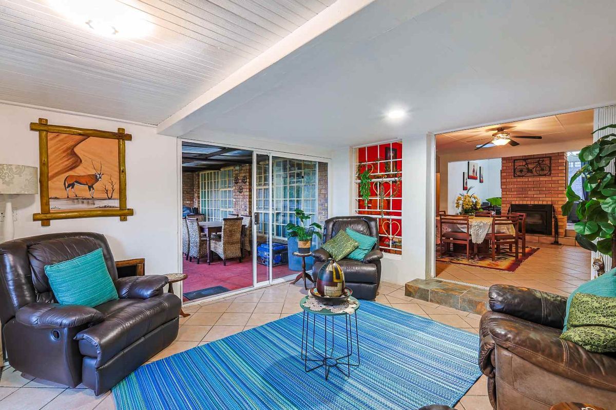 Spacious living area featuring tiled floors, sliding glass doors leading to an outdoor patio, and an adjacent dining room with a fireplace.