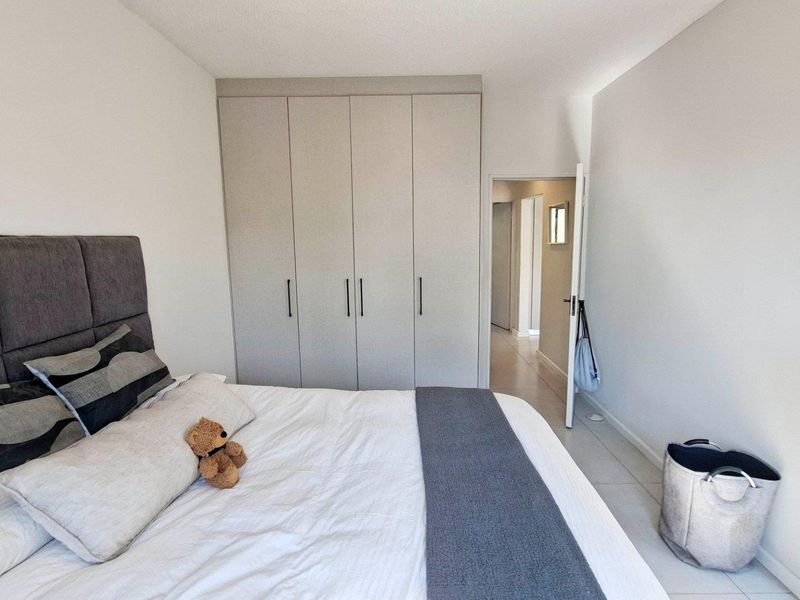 A well-maintained bedroom featuring neutral-toned built-in cupboards and clean tiled flooring, offering a bright and functional living space.