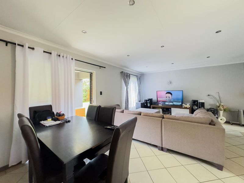 Spacious open-plan living and dining area featuring neutral tiled flooring, recessed lighting, and direct access to an outdoor patio through sliding glass doors.