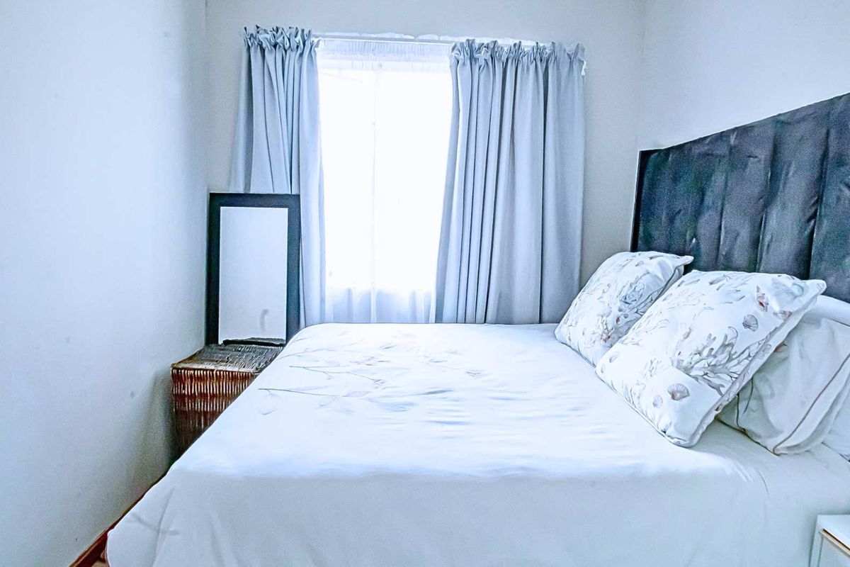 A compact bedroom featuring a window with curtains and neutral wall finishes.