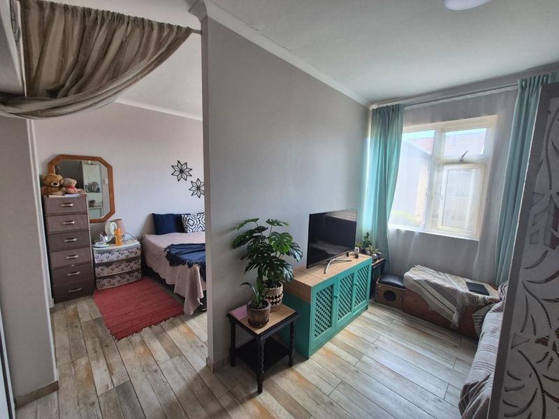 Open plan living and bedroom area featuring tiled flooring and a central partition wall, providing a functional layout for apartment living.