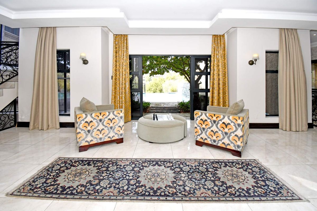 Spacious living area featuring polished tile flooring, recessed ceiling detail, and large sliding doors opening to an outdoor pool area.
