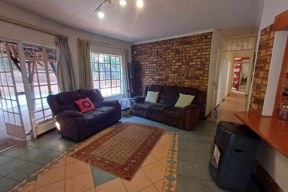 Spacious living room featuring a prominent exposed brick feature wall, tiled flooring, and direct access to the outdoor patio area.