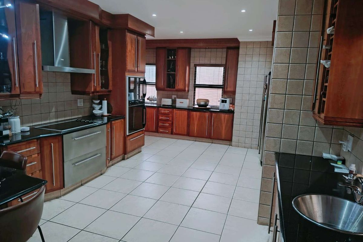 Spacious kitchen featuring extensive wooden cabinetry, granite countertops, built-in oven, electric hob, and tiled flooring with recessed lighting.