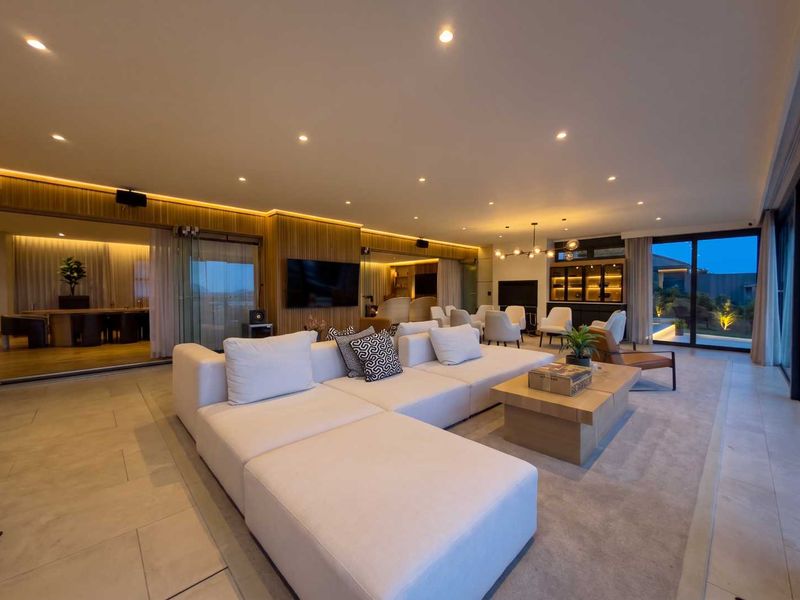 Spacious open-plan living area featuring modern timber wall paneling, recessed downlights, cove lighting, and large sliding glass doors leading to the outdoor space.