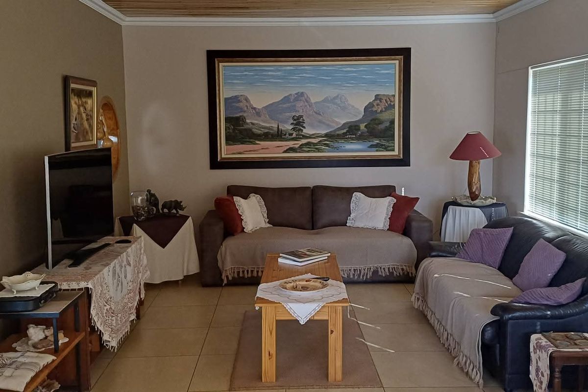 A comfortable living room featuring tiled flooring, a timber-paneled ceiling, and large windows with fitted blinds, providing a warm and inviting atmosphere.