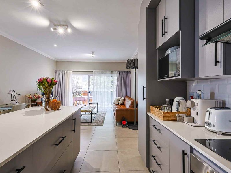 Modern open-plan kitchen and living area featuring sleek cabinetry, a central island, and seamless flow to a private balcony through sliding glass doors.