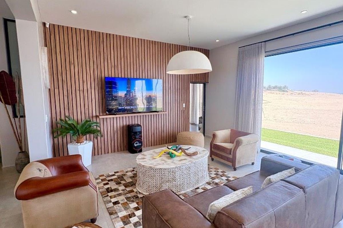 Modern living room featuring a decorative timber slat feature wall, large format floor tiles, and expansive sliding glass doors leading to an outdoor area.