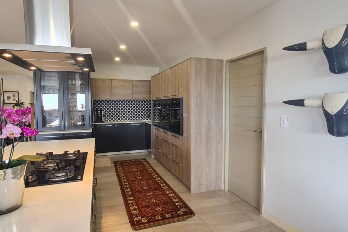 Modern kitchen featuring two-tone cabinetry, a central island with a built-in gas hob, stainless steel extractor fan, and integrated oven.